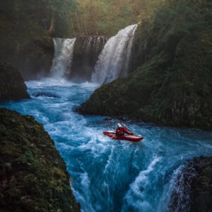 person on watercraft near waterfall